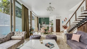 A spacious living room with a marble coffee table, two sofas, and a dining area with a chandelier. - Nerul Nirvana Nest by Dia Hotels (Nerul)