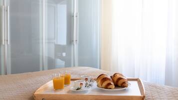 Un plateau de petit-déjeuner avec des croissants et du jus d’orange, posé sur un lit dans une chambre d’hôtel.