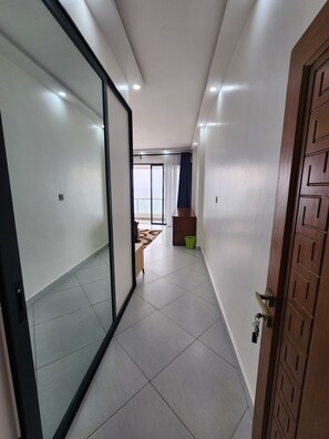 A hallway with a sliding glass door leading to a balcony with a view. - Luopian Executive Penthouse (Mombasa)