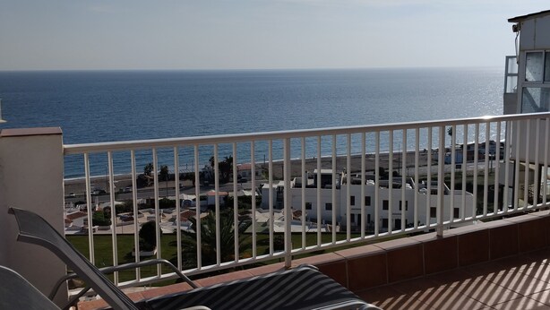Un balcon avec vue sur la mer et sur un quartier résidentiel.