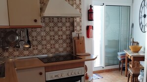 Une cuisine équipée d’une cuisinière, d’un four et de divers ustensiles. On y trouve également un coin repas avec une table et des chaises.