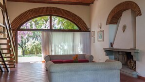 A living room with a sofa, a fireplace, and a staircase. - Residence La Canova II (Marina di Grosseto)