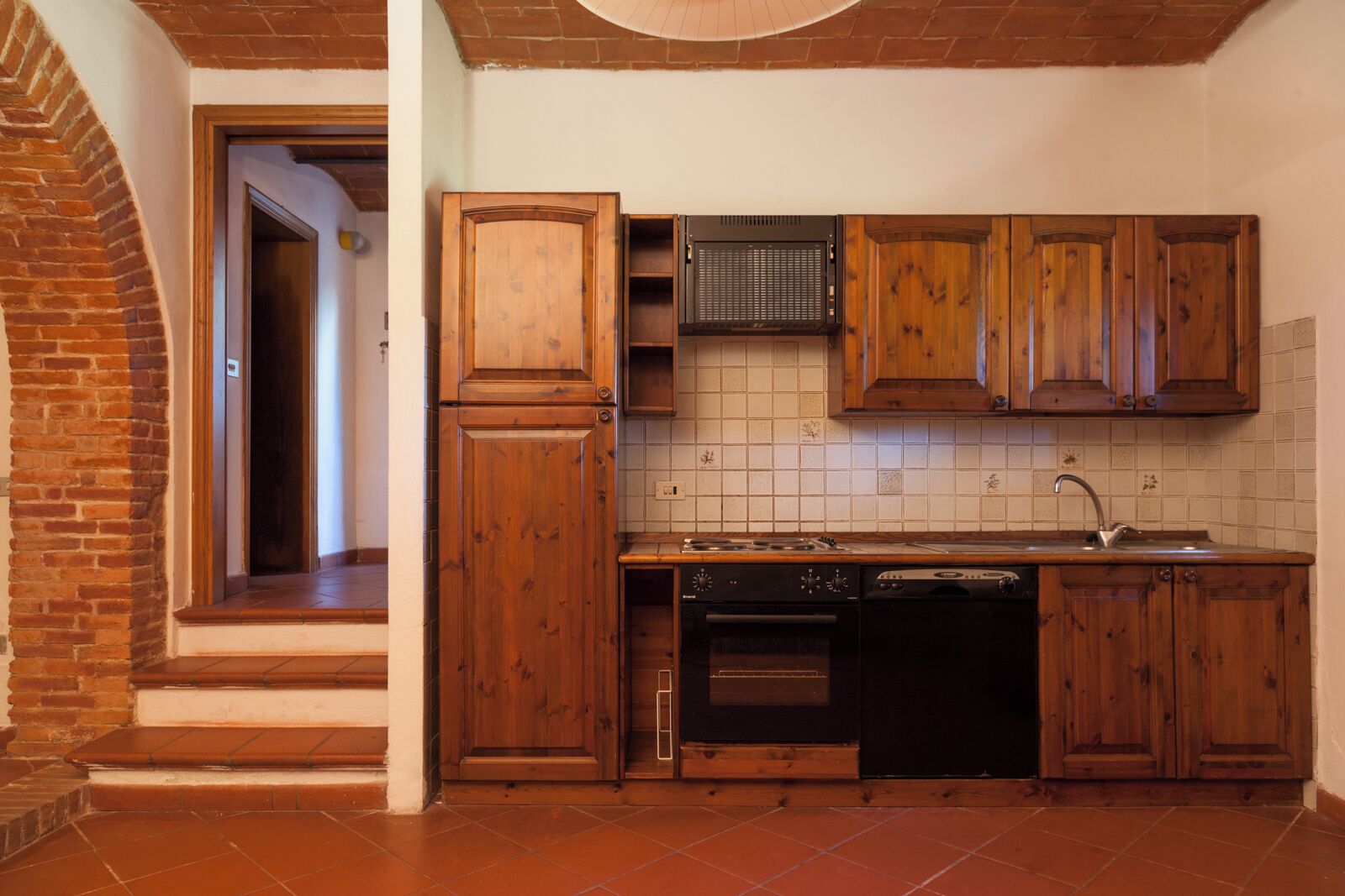 Cuina amb armaris de fusta, salabanc de rajola i forn encastrat juntament amb un esbandidor.