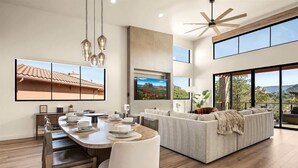 Un soggiorno moderno con zona pranzo, ampie finestre e ventilatore a soffitto.