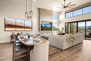 A modern living room with a dining area, large windows, and a ceiling fan. - Hilltop Retreat Spectacular Red Rock Mtn Views! Be (Sedona)