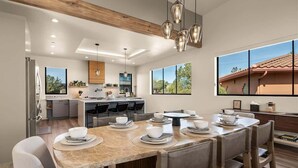 Una cucina moderna con zona pranzo, ampie finestre e vista su una casa.
