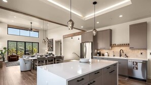 Una cucina moderna con una grande isola, illuminazione a sospensione e un'area pranzo con vista.