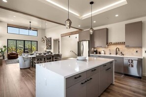 A modern kitchen with a large island, pendant lighting, and a dining area with a view. - Hilltop Retreat Spectacular Red Rock Mtn Views! Be (Sedona)