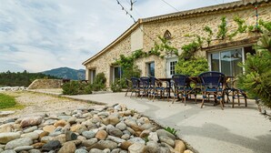 Ein Steingebäude mit Terrasse, Sitzgelegenheiten im Freien und einem Felsengarten.