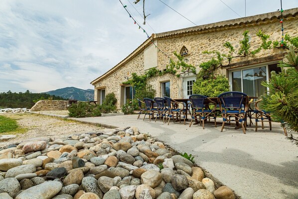 A stone building with a patio, outdoor seating, and a rocky garden area.