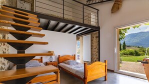 Ein Schlafzimmer mit einem Holzbett, einem Holztisch und einer Treppe, die zu einer oberen Ebene führt.