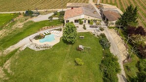 Eine Luftaufnahme eines Hauses mit Schwimmbad, umgeben von einer gepflegten Rasenfläche und Weinbergen.