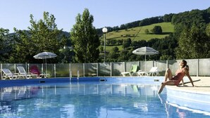 A swimming pool with lounge chairs and umbrellas, surrounded by a fence and trees. - Apartment in Saint-geniez by Lot River (Saint-Geniez-d'Olt-et-d'Aubrac)