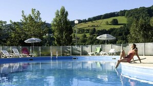 A swimming pool with lounge chairs and umbrellas, surrounded by a fence and trees. - Apartment in Saint-geniez by Lot River (Saint-Geniez-d'Olt-et-d'Aubrac)