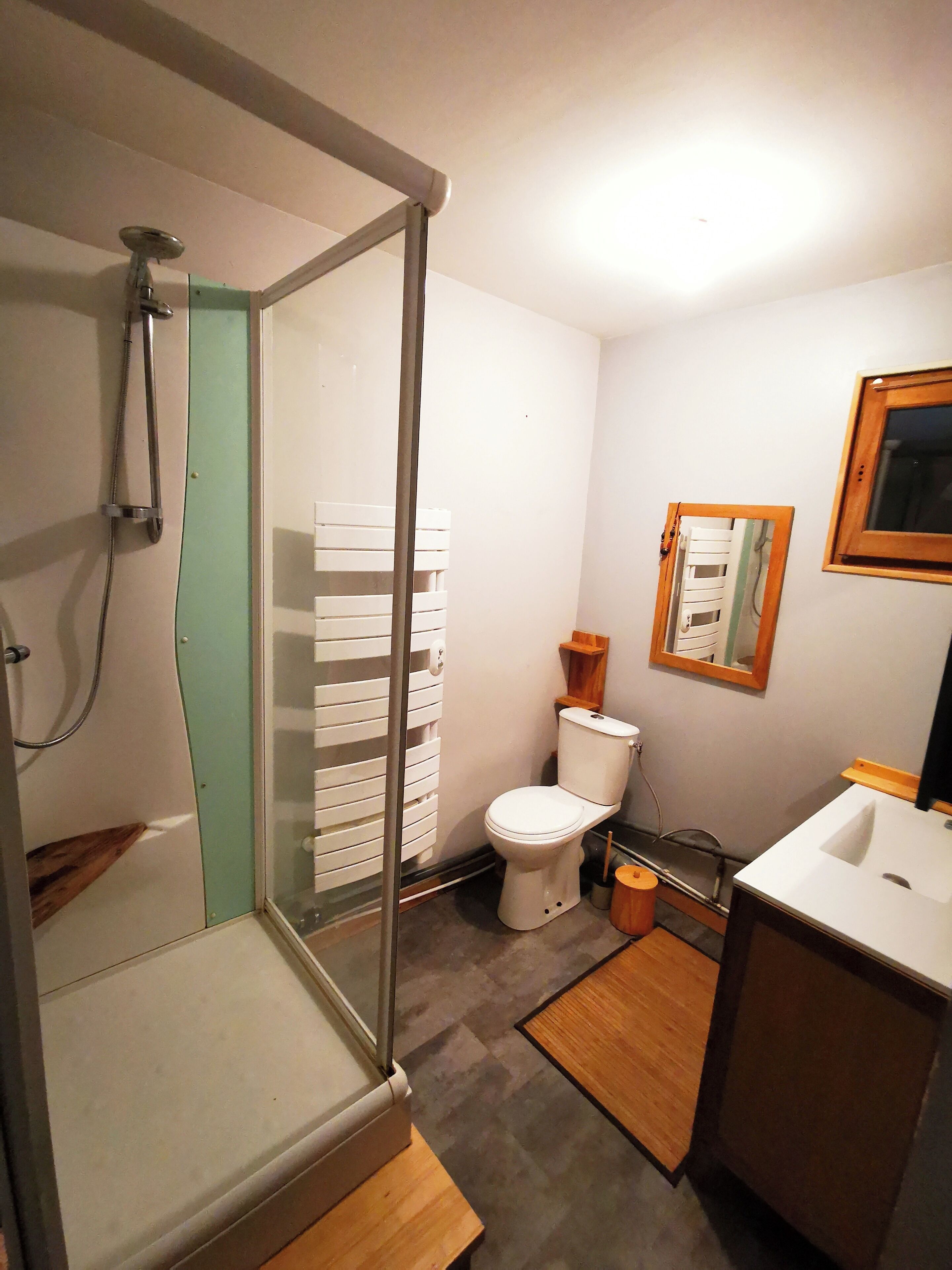 Un baño con ducha corredera de vidrio, inodoro y lavamanos.