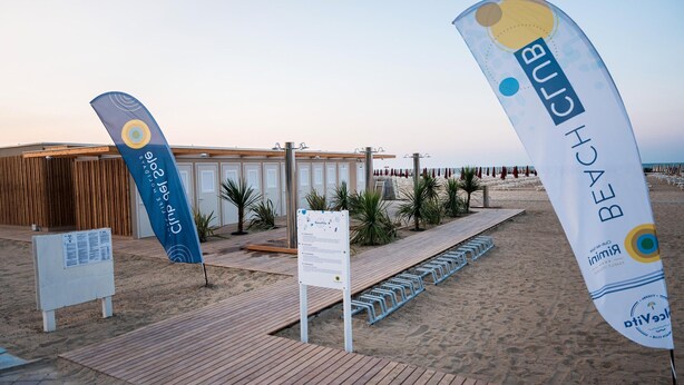 A beachside hotel with a wooden deck, a signboard, and two banners. - Friendly Mobile Home in Rimini Family Village (Rimini)