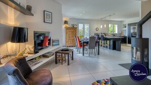 Een moderne woonkamer met een televisie, bank en eethoek.