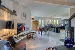 Ein modernes Wohnzimmer mit Fernseher, Sofa und Essbereich.