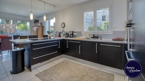 Een moderne keuken met zwarte kasten, een groot kookeiland en hanglampen.