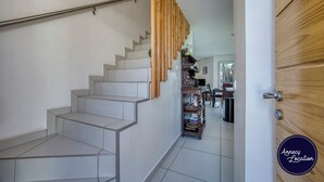 Een trap met een modern ontwerp, een houten deur en uitzicht op een eetruimte.