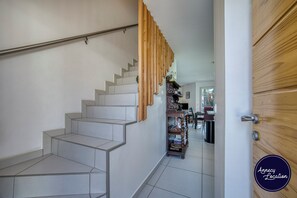 Eine moderne Treppe, eine Holztür und ein Blick in einen Essbereich.