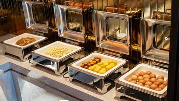 Un bufé con diferentes alimentos en recipientes de metal.