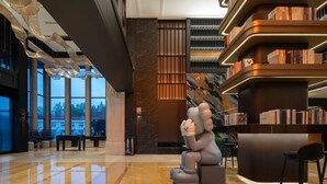 Un hall d’entrée spacieux, doté d’une grande fenêtre, d’une statue et d’une bibliothèque.