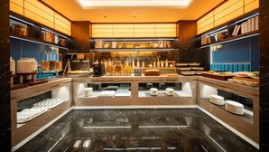 Un buffet disposé de manière à présenter une zone centrale de service, plusieurs étagères remplies de différents plats et un sol en marbre.