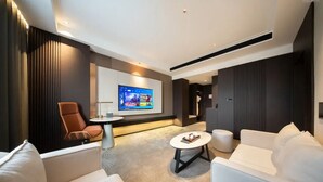 Un salon moderne avec un téléviseur à écran plat, des canapés blancs, une table basse et un tapis à motifs.
