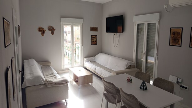Ett modernt vardagsrum med en soffa, ett matbord och en tv som är monterad på väggen.
