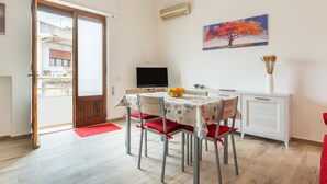 A dining area with a table, chairs, a TV, and a painting on the wall.