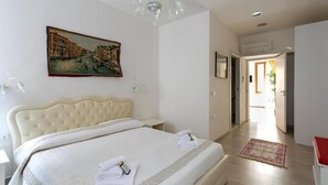 Um quarto com uma cama grande, um quadro na parede e um corredor que leva a outro cômodo.