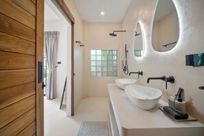 Un baño moderno con dos lavamanos blancos, un espejo grande y una ducha.