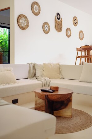 Ein modernes Wohnzimmer mit einem weißen Sofa, einem runden Couchtisch und Wanddekoration.
