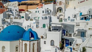 Ένα λευκό κτίριο με έναν μπλε τρούλο και μια σκάλα που οδηγεί σε ένα μπαλκόνι.