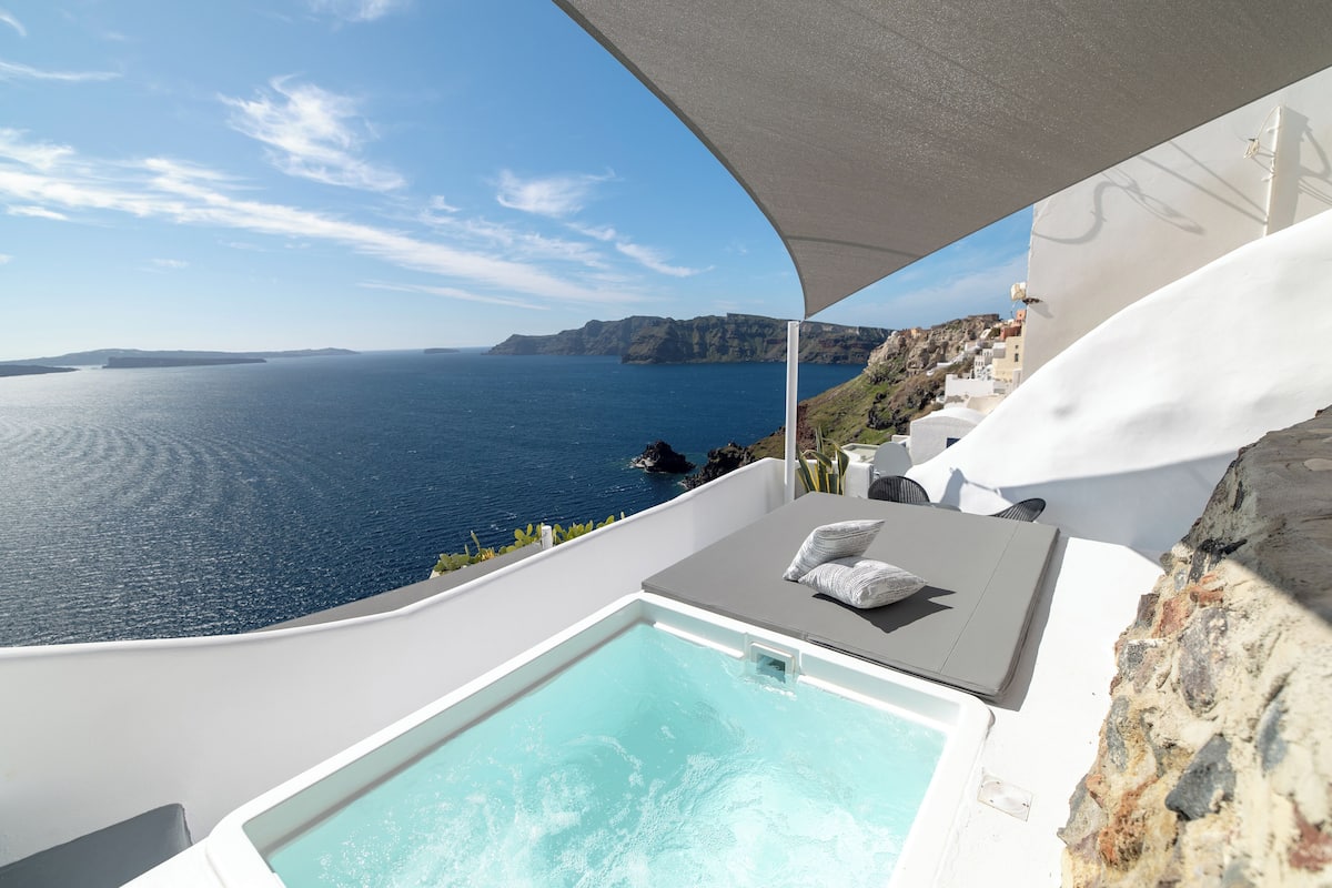 Un balcon privé avec vue sur la mer, un jacuzzi et un coin salon avec un coussin.