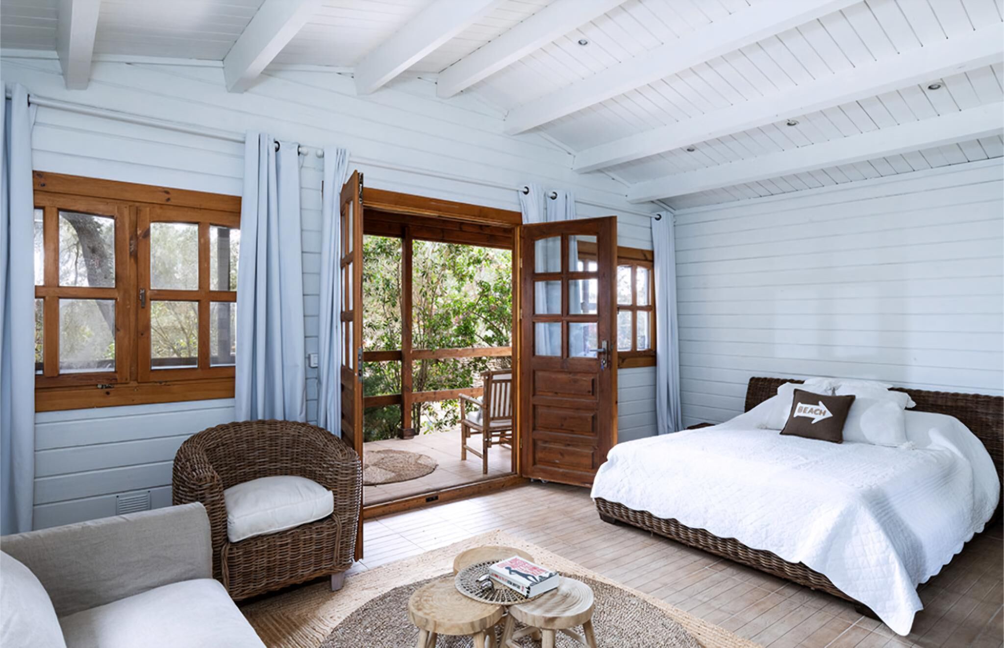 A bedroom with a bed, a chair, a small table, and a window.