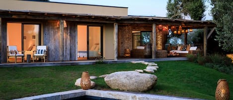 A modern house with a swimming pool, outdoor seating, and a stone pathway.