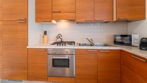 A modern kitchen with wooden cabinets, stainless steel appliances, and a white countertop. - Antico Lavatoio Valbrona (Valbrona)