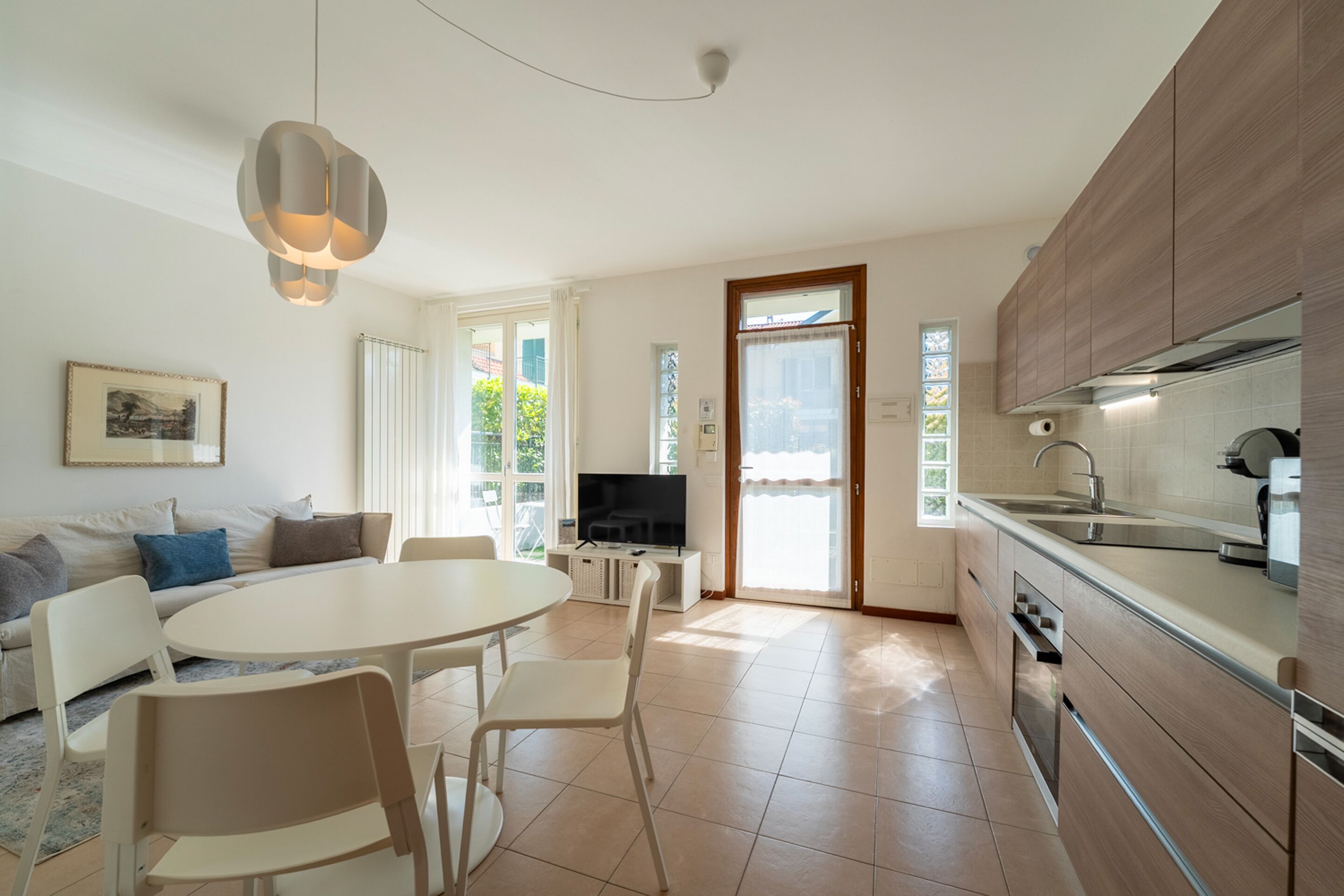 Una cucina moderna con zona pranzo, televisore e una grande finestra.