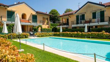 Una piscina rodeada por un césped cuidado y una hilera de edificios de dos pisos con balcones.