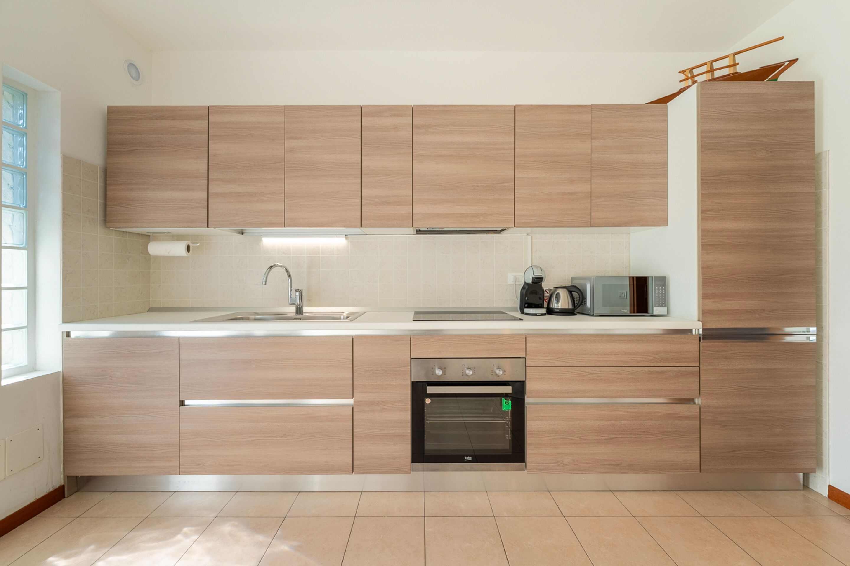 Eine moderne Küche mit Holzschränken, einem Backofen, einer Mikrowelle und einer Kaffeemaschine.