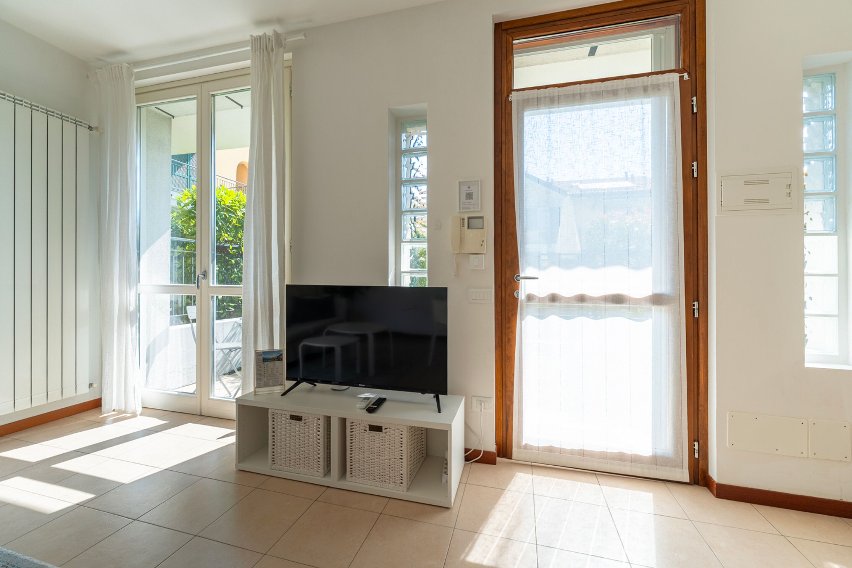 Ein Wohnzimmer mit Flachbildfernseher, einer Schiebetür und Blick ins Grüne.