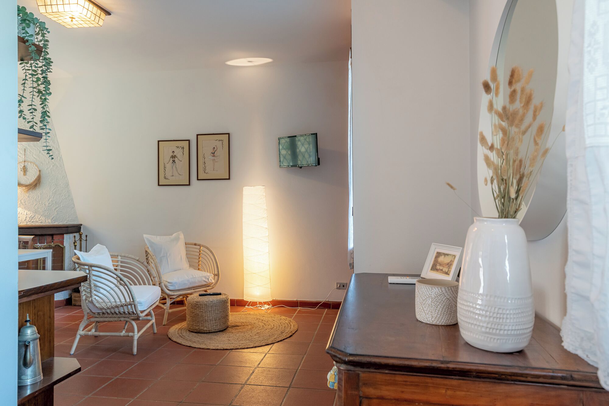 Una sala de estar acogedora con una mesa de centro de madera, sillas de mimbre, un tapiz tejido y un espejo grande.