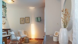 Ein gemütliches Wohnzimmer mit einem Holztisch, Korbstühlen, einem gewebten Teppich und einem großen Spiegel.