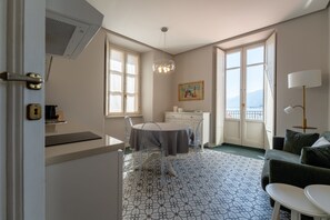 Une pièce comprenant une table à manger, des chaises, un canapé, une lampe et un tableau au mur.