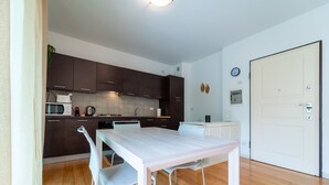 A compact kitchen with dark cabinets, a white dining table, and a white door. - Como Modern Bellinzona (Como)