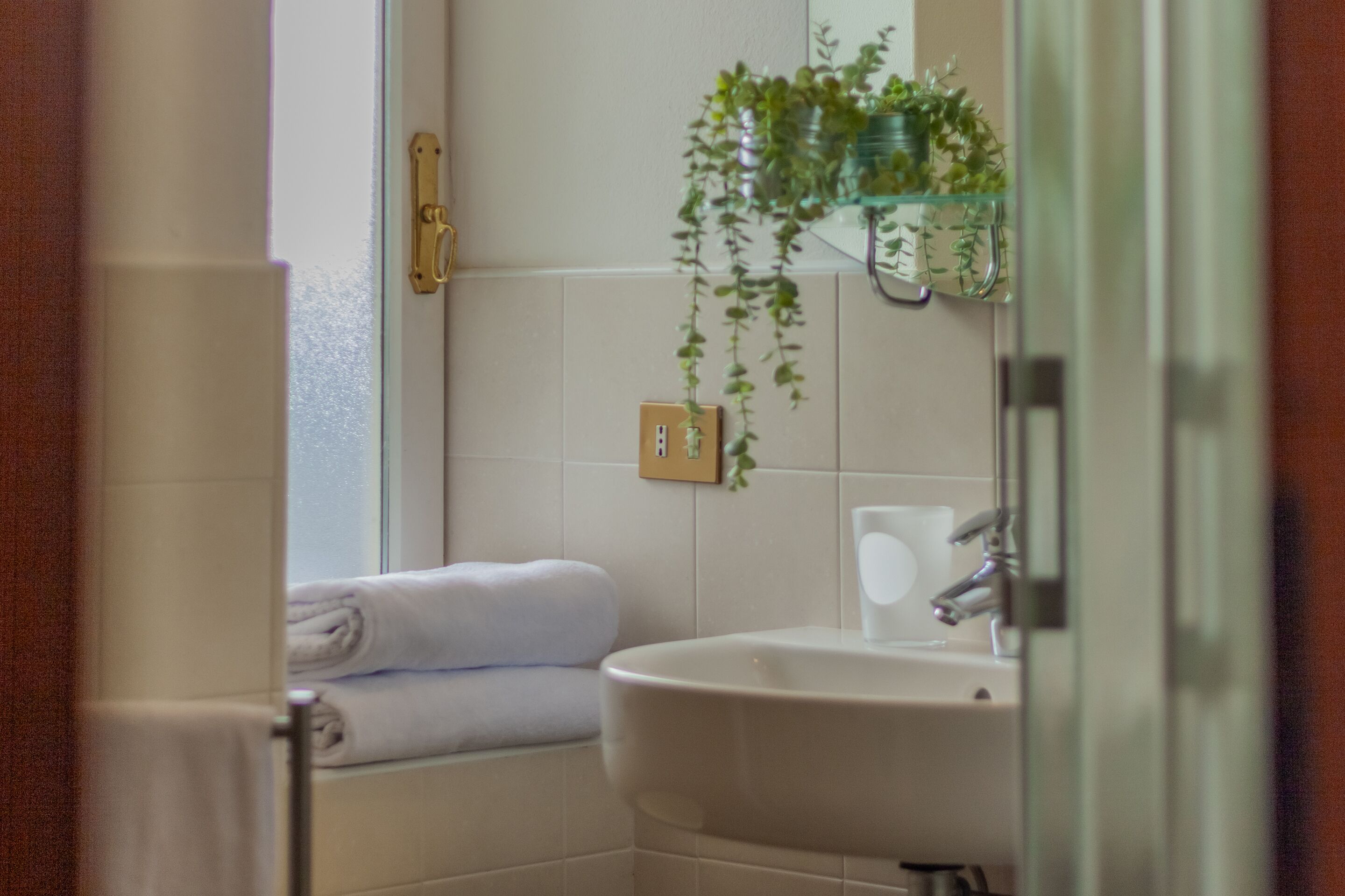 Une salle de bain avec un lavabo blanc, une cabine de douche en verre et un porte-serviettes avec des serviettes pliées.