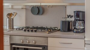 Eine Küche mit Gasherd, Backofen und Kaffeemaschine.