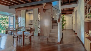 A spacious living area with a wooden staircase, a dining table with chairs, and a view of the outdoors. - Domus Elena Lakeview (Bellagio)